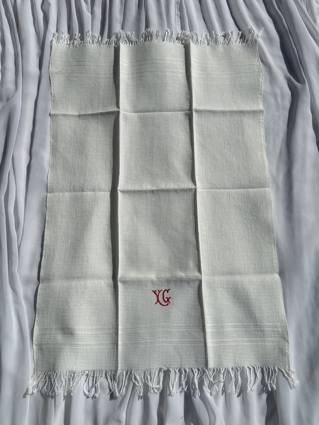 Bílá utěrka s červeným monogramem a třásněmi