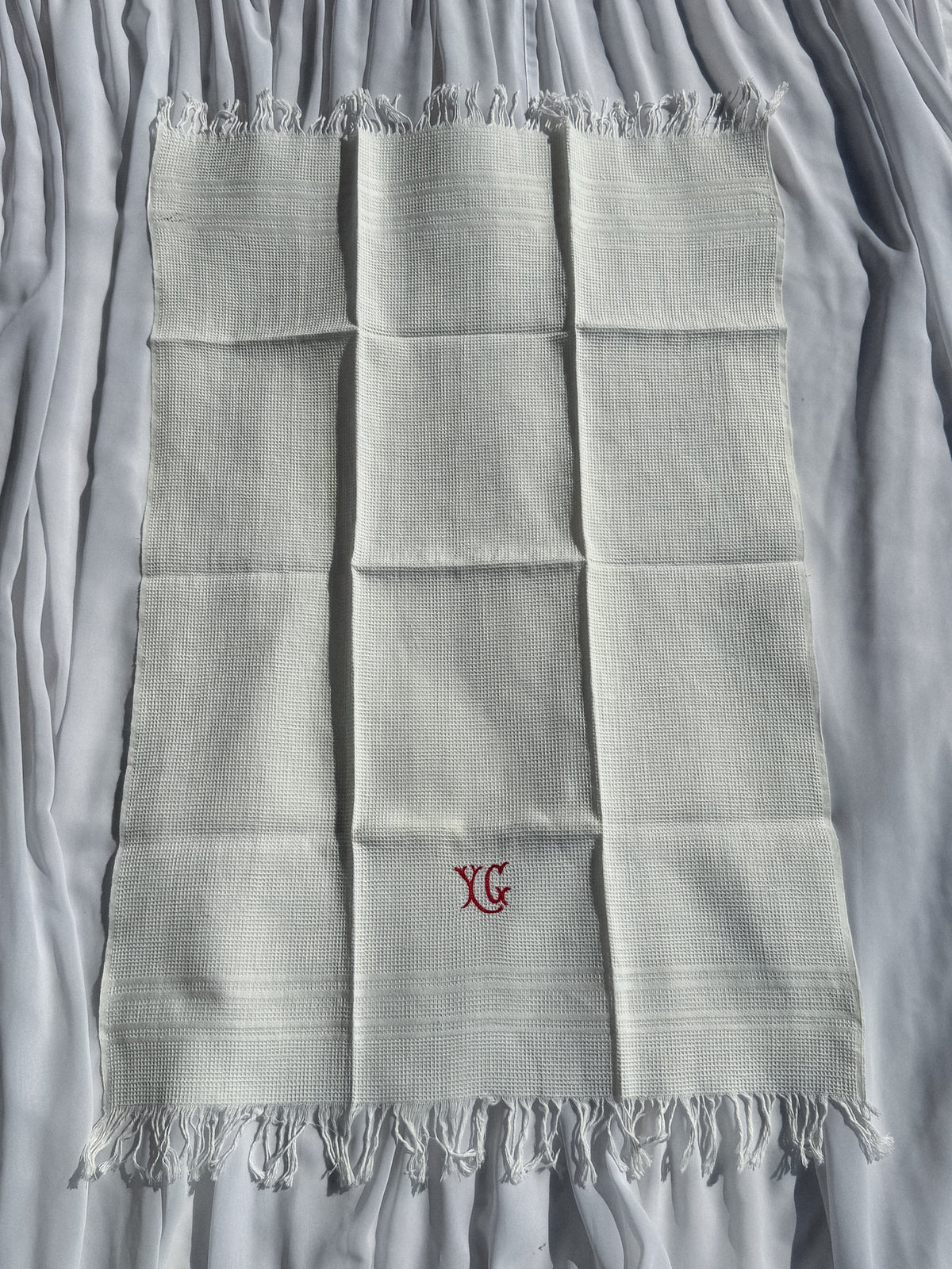 Bílá utěrka s červeným monogramem a třásněmi