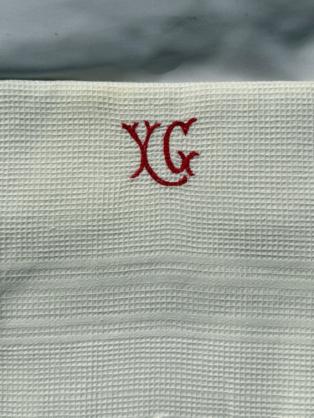 Bílá utěrka s červeným monogramem a třásněmi
