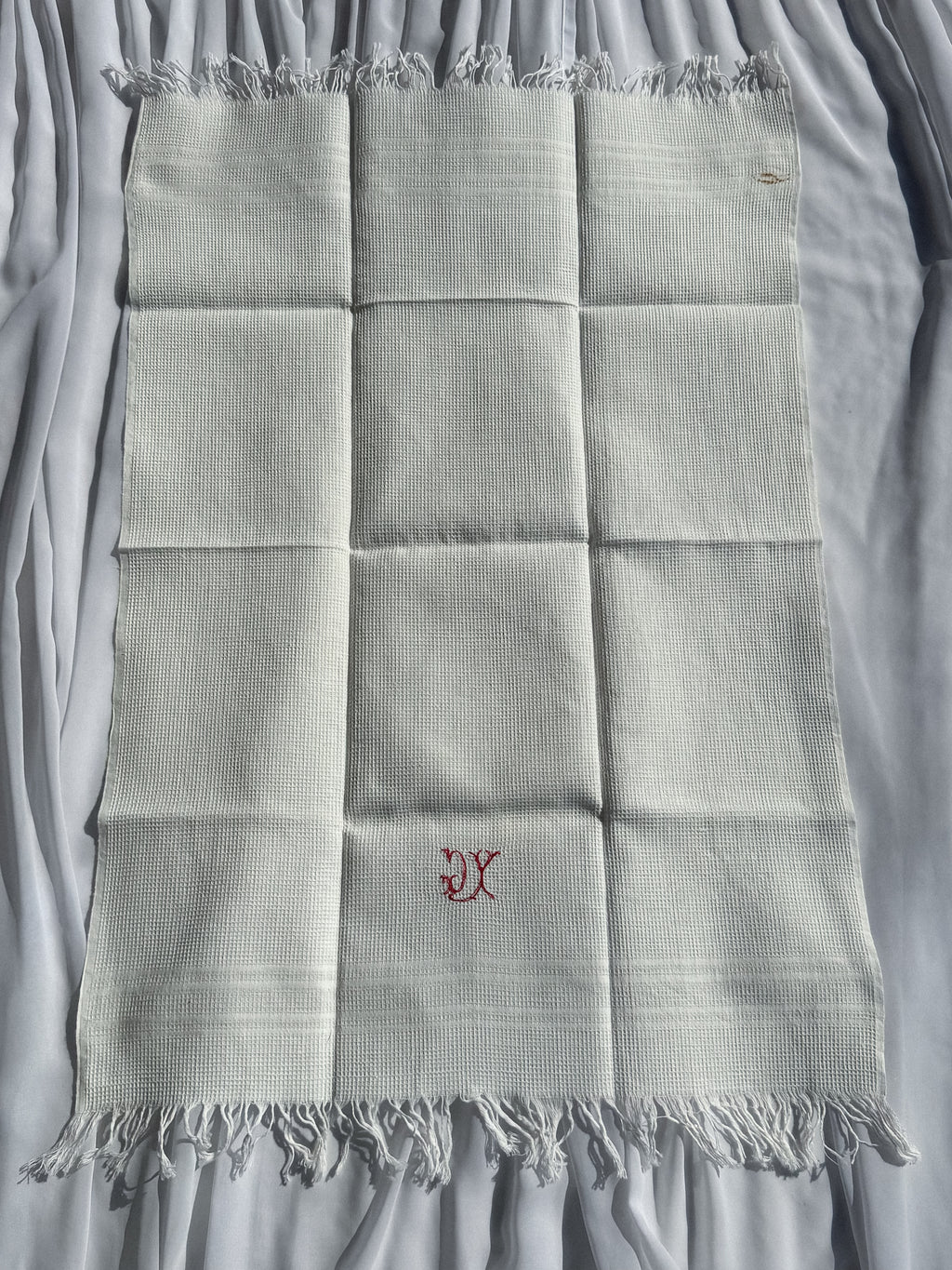 Bílá utěrka s červeným monogramem a třásněmi