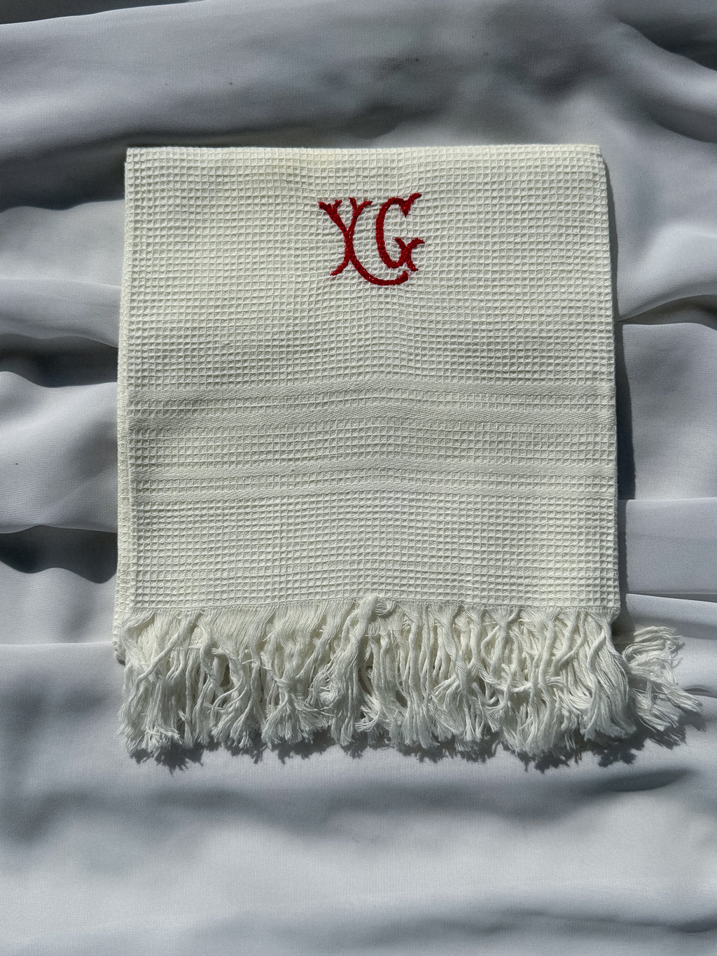 Bílá utěrka s červeným monogramem a třásněmi