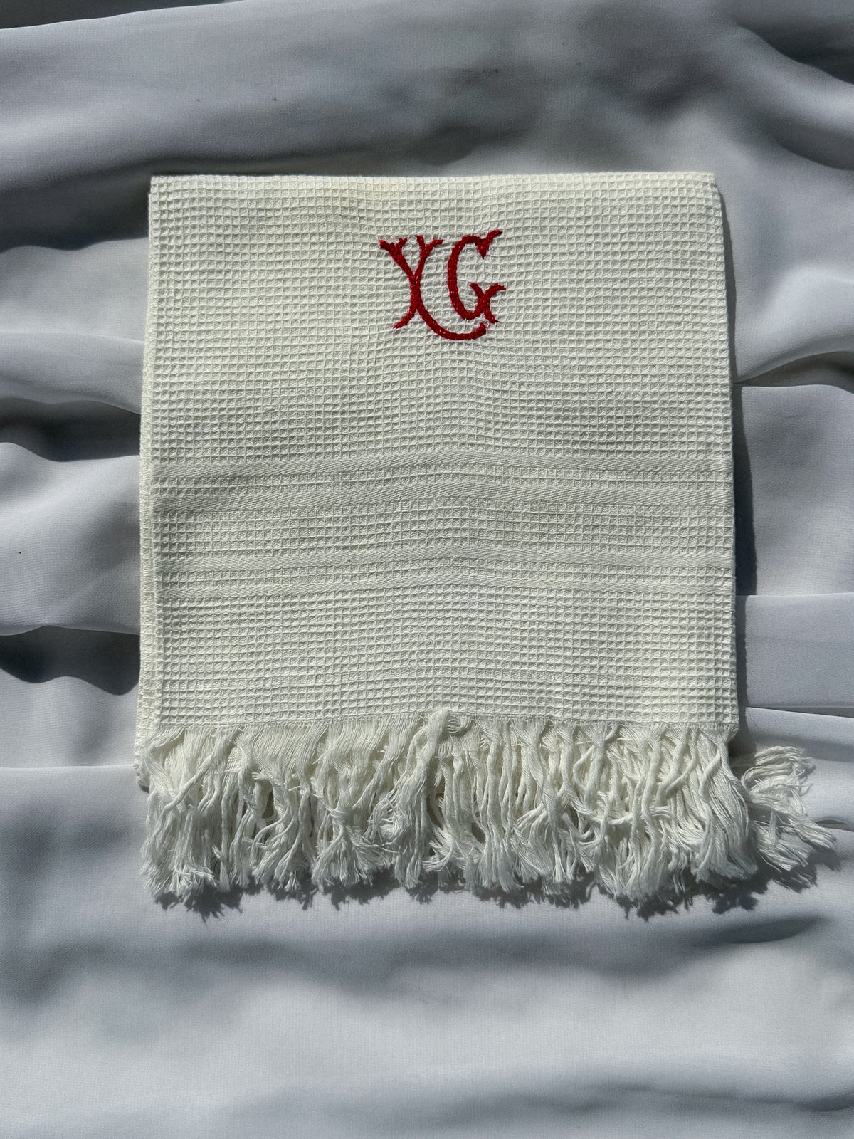 Bílá utěrka s červeným monogramem a třásněmi