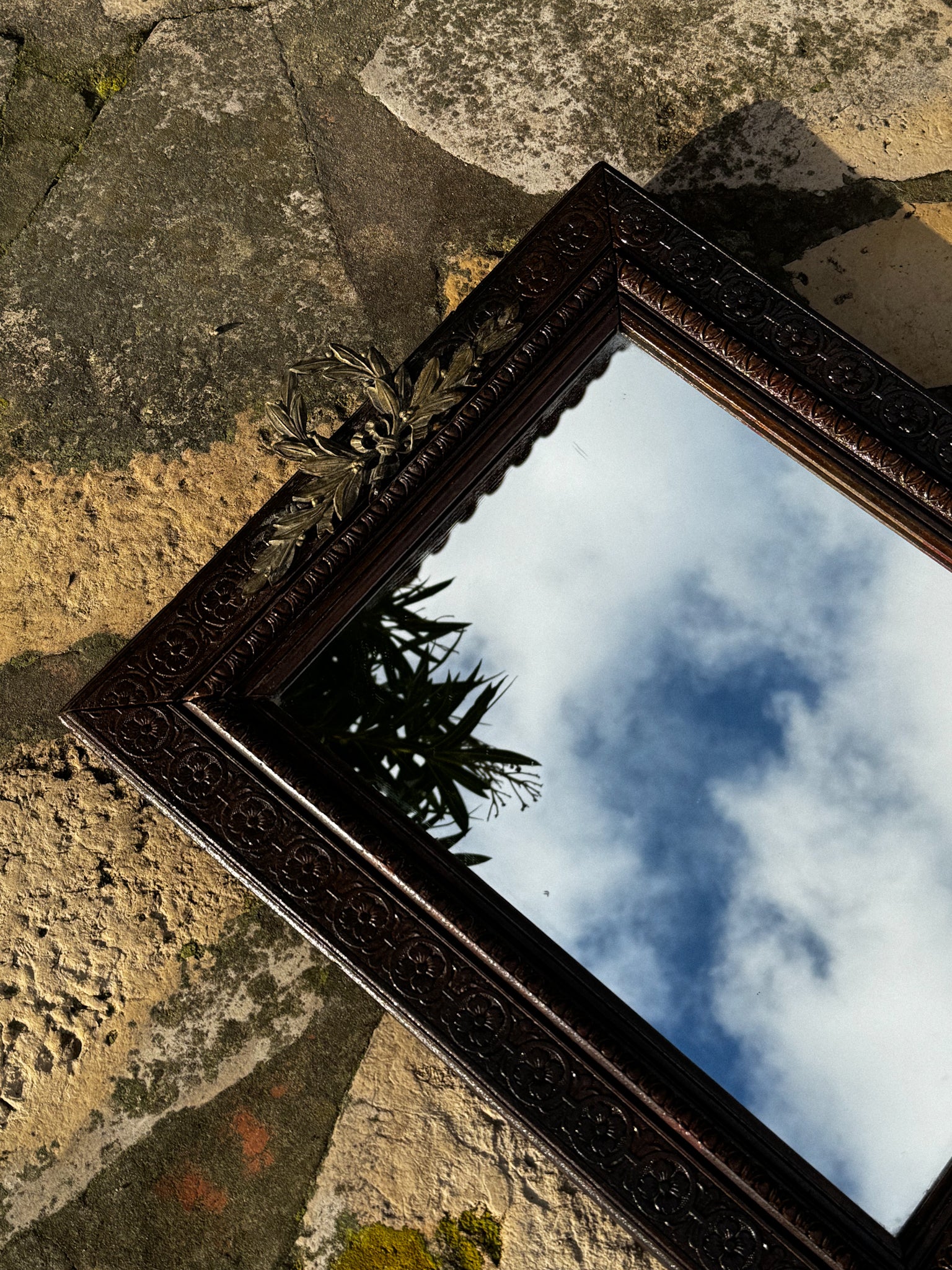 Starožitné zrcadlo s bohatě zdobeným rámem a horním ornamentem